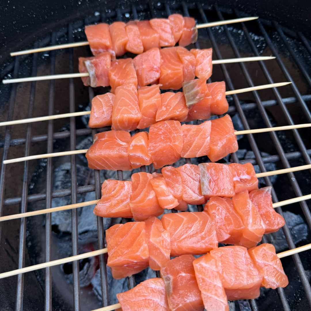 SASHIMI kokybės atlantinės lašišos filė be odos gabalėliai, suverti ant medinių iešmelių ir paruošti kepimui virš žarijų grilyje